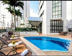 a swimming pool with lounge chairs and a building at Um lar aconchegante na rota do sol in Natal