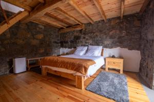 a bedroom with a bed and a stone wall at Ribeirinha 94 in Ribeirinha