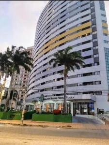 a large building with palm trees in front of it at Um lar aconchegante na rota do sol in Natal