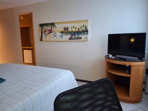 a bedroom with a bed and a flat screen tv at Um lar aconchegante na rota do sol in Natal +8 photos