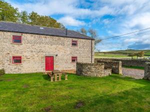 a brick building with a red door and a bench at 4 Bed in Hexham oc-78159 in Catton