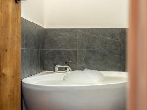 a bathroom with a white sink and gray tiles at 4 Bed in Hexham oc-78159 in Catton +21 photos
