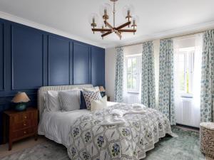 a bedroom with blue walls and a bed and a chandelier at 5 Bed in Lymington oc-96189 in Sway