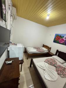 a room with two beds and a table and a tv at Hotel D'Aldeia Cametá in Cametá
