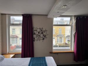 a bedroom with a bed and two windows at The Clarendon Hotel in Blackpool