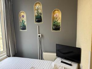 a bedroom with three pictures of flowers on the wall at The Clarendon Hotel in Blackpool
