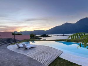 ein Pool mit zwei weißen Stühlen und Blick auf das Meer in der Unterkunft Ruma Mahavidna in Kintamani + 18 Fotos