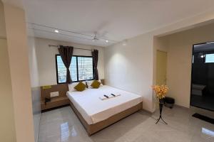 a bedroom with a large white bed and a television at Indraprastha Executive Lodging in Pune