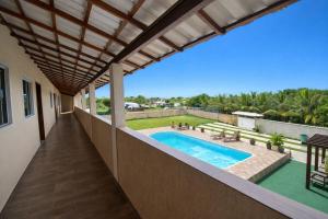 an outdoor patio with a swimming pool and a roof at Suites Lara Jackson in Saquarema