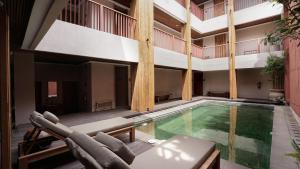 an indoor swimming pool with chairs and a building at Uma Tilu By Seken Living in Yogyakarta