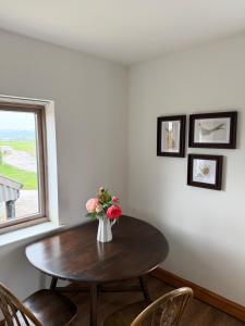 a dining room table with a vase of flowers on it at Flat 2, Coneygre Farm in Hoveringham