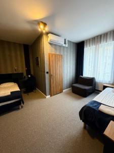 a hotel room with a bedroom with a bed and a chair at City Tour Apartamenty in Poznań