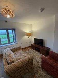 a living room with a couch and a television at Flat 2, Coneygre Farm in Hoveringham