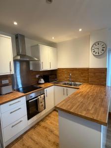 a kitchen with white cabinets and a clock on the wall at Flat 2, Coneygre Farm in Hoveringham