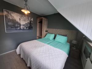 a small bedroom with a bed with blue pillows at Zee-en-Zo Noordwijk in Noordwijk
