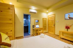 a bedroom with a bed and a desk with a television at Lucky Phu Quoc Hotel in Phú Quốc