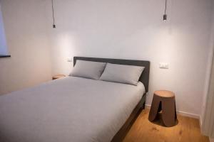 a bedroom with a white bed with two tables at ZiviNest in Pergine Valsugana
