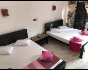 a bedroom with two beds and a table with a pink pillow at Green Haven Yala Safari Retreat in Tissamaharama