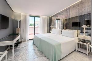 a bedroom with a large white bed and a desk at AZZ Mérida Medea Hotel in Mérida