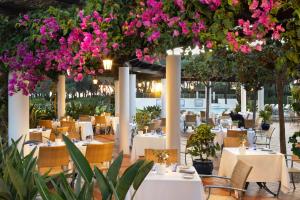 ein Restaurant mit Tischen und von der Decke hängenden Blumen. in der Unterkunft Pine Cliffs Suites in Albufeira