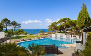 Ein Swimmingpool mit Liegestühlen und dem Meer im Hintergrund in der Unterkunft Pine Cliffs Suites in Albufeira