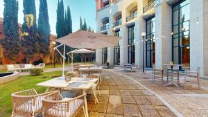 a patio with tables and chairs and an umbrella at AZZ Mérida Medea Hotel in Mérida