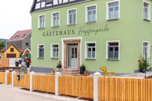 a green building with a fence in front of it at Apartment "Hopfenblume" in Spalt +5 photos