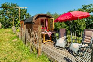 a small wooden house with a red umbrella and chairs at Weinbergsauna in Großweingarten