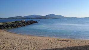 a beach with blue water and rocks and mountains at The Old Coastguard Lodge in Dingle