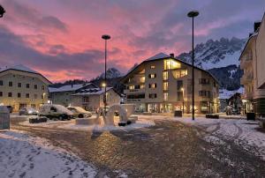 a building with a fountain in the snow at sunset at Post Residence - Home of Memories - Dolomites in San Candido