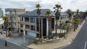 a house with palm trees in front of a street at De Ocean Lane Guest House in Cape Town