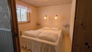 a bedroom with a bed with white sheets and a window at Stor älg in Dalskog