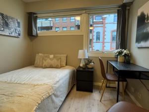 a bedroom with a bed and a desk and a window at Kongensgate Apartments in Kristiansand