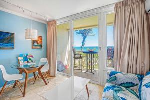 a living room with a table and a view of the ocean at Islander on the Beach 249 in Kapaa