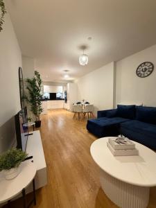 a living room with a blue couch and a table at Prestige London Apartment Balcony Views in London