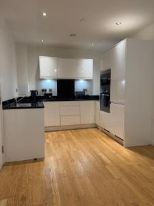 a kitchen with white cabinets and a wooden floor at Prestige London Apartment Balcony Views in London