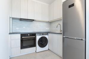 a white kitchen with a washer and a dishwasher at Penthouse Seafront Luxury Studio in Epanomi