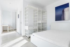 a white bedroom with a bed and a book shelf at Penthouse Seafront Luxury Studio in Epanomi