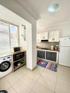 a kitchen with white cabinets and a washer and dryer at Mina résidence A2 in Kelibia