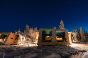 a cabin in the snow at night with lights at Lapland Glow Chalets in Rovaniemi