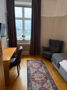 a bedroom with a bed and a desk and a window at Hamnhotellet Kronan in Landskrona