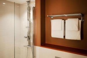 a bathroom with a shower and towel rack with towels at Scandic Go, Saaristonkatu 1 in Oulu +19 photos