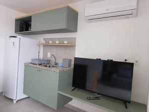 a kitchen with a flat screen tv and a refrigerator at Flat em Tamandaré - 102 - Carneiros Beach Exclusive in Tamandaré