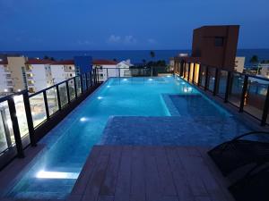 a swimming pool on the roof of a building at night at Flat em Tamandaré - 102 - Carneiros Beach Exclusive in Tamandaré