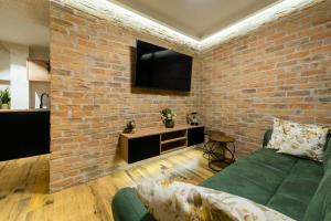 a living room with a brick wall and a green couch at Deluxe Dino room & studio apartment by Adex travel in Zadar