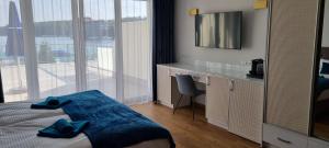 a bedroom with a bed and a desk with a television at Villa LeLux in Mikołajki