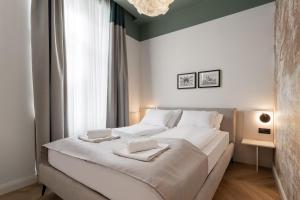 a bedroom with a large white bed with towels on it at Catalog Boutique Rooms Debrecen in Debrecen