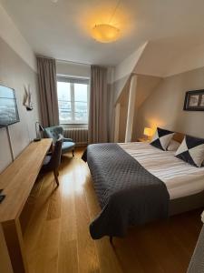 a bedroom with a bed and a desk and a chair at Hamnhotellet Kronan in Landskrona