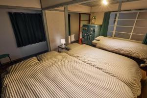 two twin beds in a room with at Hinosawa Riverside Lodge 水遊び宿日野沢 in Minano