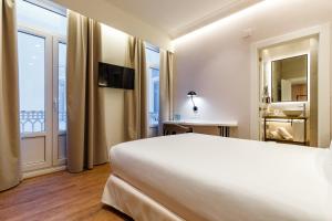 a hotel room with a bed and a balcony at Petit Palace Plaza de la Reina in Valencia